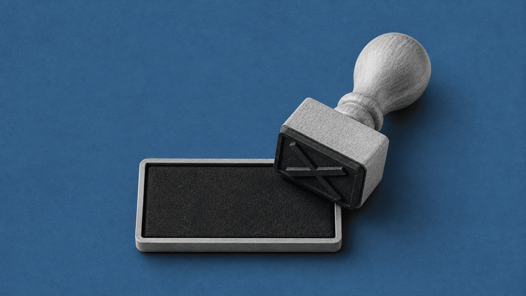 A wooden rubber stamp resting on a black ink pad against a blue background